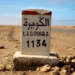 Architectural rendering of a luxurious tourism village in Lagouira, Morocco, featuring hotels, a marina, and desert landscapes under a clear sky.