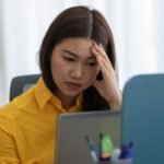 A person looking thoughtfully at a computer screen, symbolizing job search and career transition in a challenging economy.