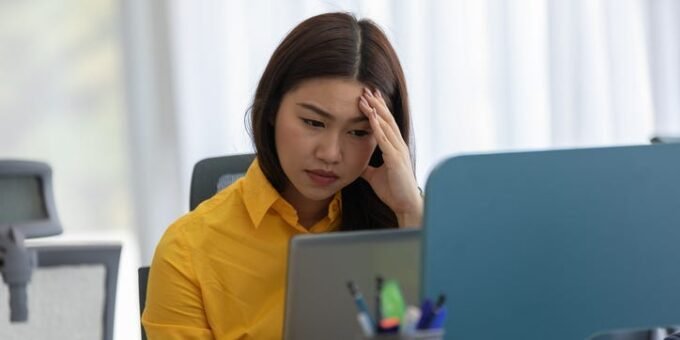 A person looking thoughtfully at a computer screen, symbolizing job search and career transition in a challenging economy.