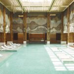 Une esthéticienne appliquant un soin Omorovicza sur le visage d'une cliente au luxueux Spa du Four Seasons Rabat, avec des produits de la marque en arrière-plan.