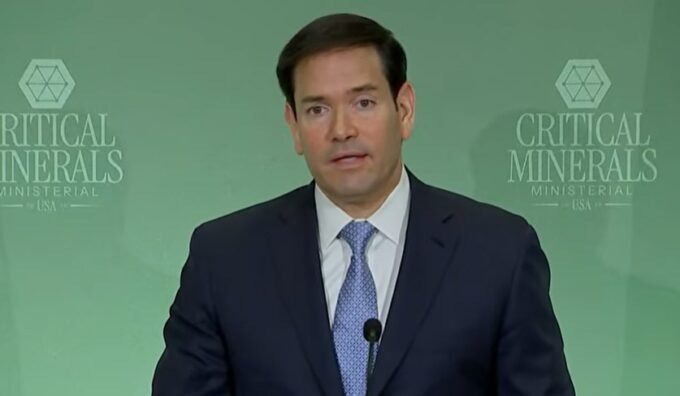 Marco Rubio, Secrétaire d'État américain, s'exprimant lors d'une conférence de presse à Washington, avec le drapeau américain en arrière-plan.
