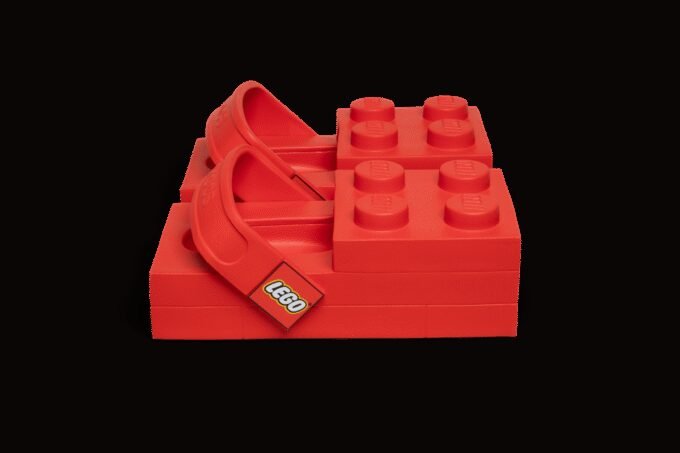 A pair of bright yellow LEGO Crocs with a LEGO minifigure, showcasing their blocky, exaggerated design.