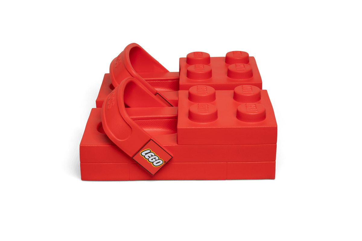 A pair of bright yellow LEGO Crocs with a LEGO minifigure, showcasing their blocky, exaggerated design.