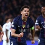 Vue aérienne du Parc des Princes illuminé, avec le logo de la Ligue des Champions affiché sur l'écran géant, symbolisant l'enjeu du match PSG-Monaco.