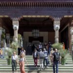 Vue panoramique de La Mamounia à Marrakech, avec des œuvres d'art contemporain africain exposées dans ses jardins luxuriants, sous un ciel bleu éclatant, symbolisant l'union de l'art et du patrimoine marocain.