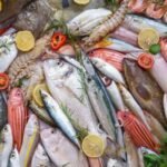 Assortiment de poissons et fruits de mer frais sur lit de glace avec citron et herbes