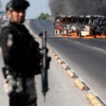 Un agent du bureau du procureur examine un bus incendié par des groupes criminels à Zapopan, Mexique, le 22 février 2026, illustrant les violences post-mortem d'El Mencho.