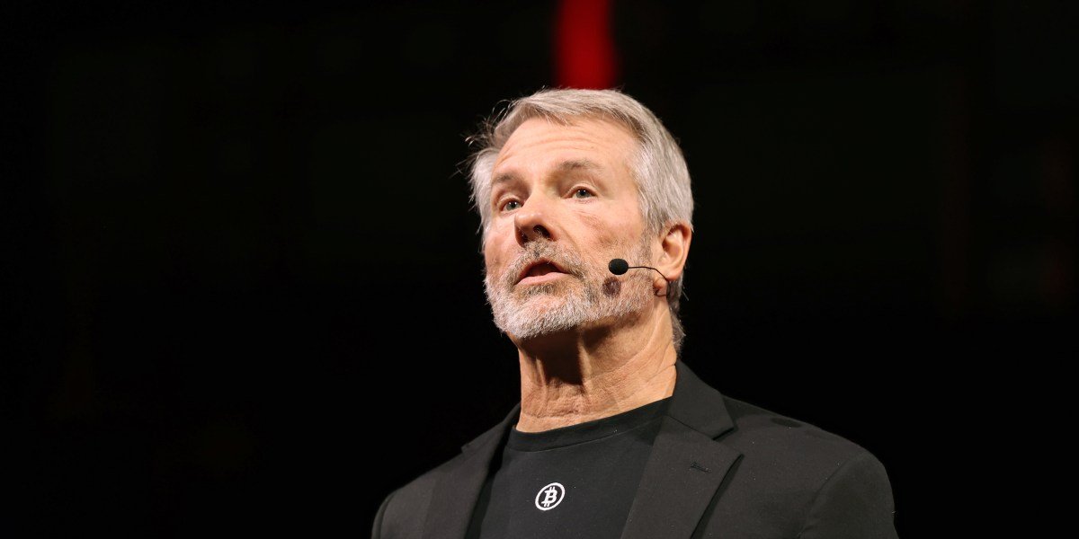 Michael Saylor's Risky Financial Gambit: The Unseen Pivot at MicroStrategy 3 Michael Saylor speaking, with Bitcoin and MicroStrategy logos in the background, symbolizing his financial strategy.