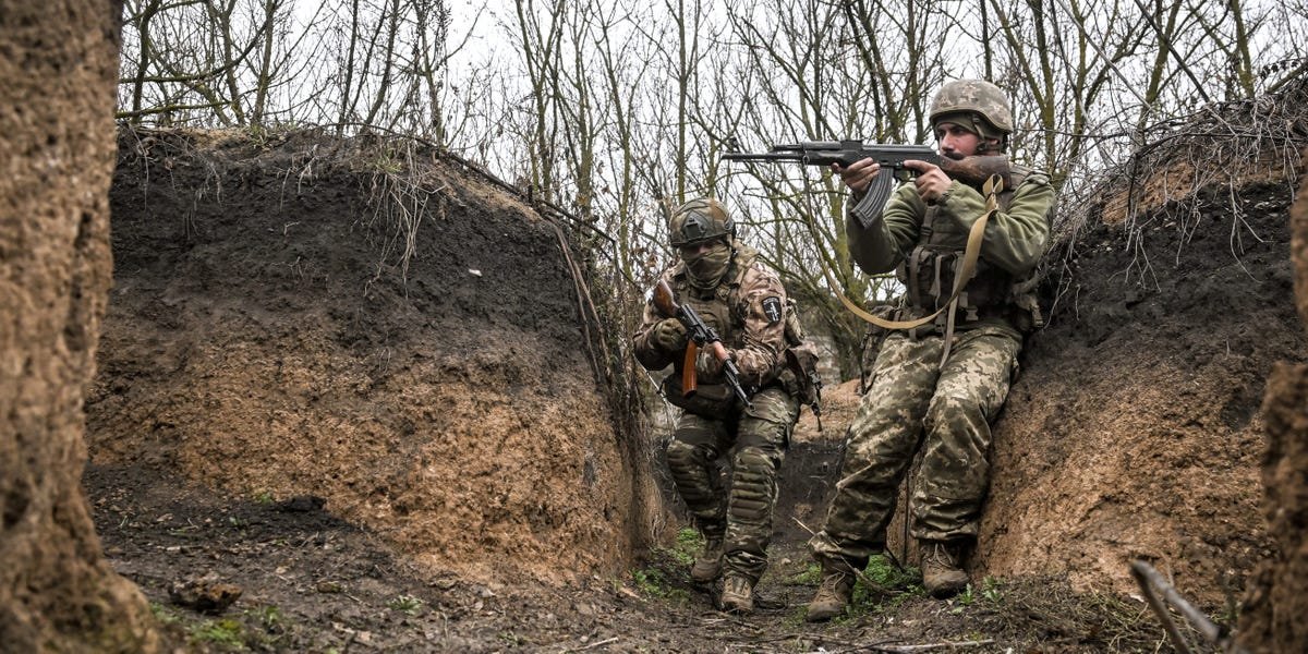Beyond the Drone Age: The Unyielding Reality of the Infantryman's Fight 3 A soldier in muddy combat gear in a trench, with a drone visible in the sky above.