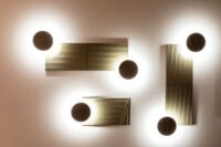 Modular ARID Wall Lighting system by Nahtrang Studio for Bover, showcasing customizable light nodes and colored back panels on a wall.