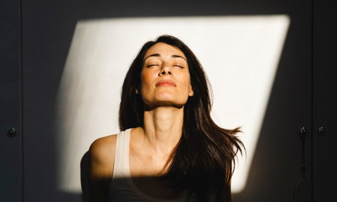 Transform Your Mornings: The 5-Minute Science-Backed Habit for Better Sleep and Energy 6 A person standing outdoors, bathed in morning sunlight, looking refreshed.