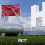 Aerial view of a green hydrogen production facility in Morocco with solar panels and wind turbines in the background, symbolizing the partnership between Spanish energy companies Acciona and Moeve with the Moroccan government.