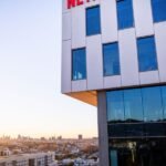 DOJ Intensifies Netflix-Warner Bros. Deal Review, Citing Creator Leverage Concerns 4 Illustration of Netflix and Warner Bros. logos with a Justice Department scale of justice, symbolizing an antitrust investigation.