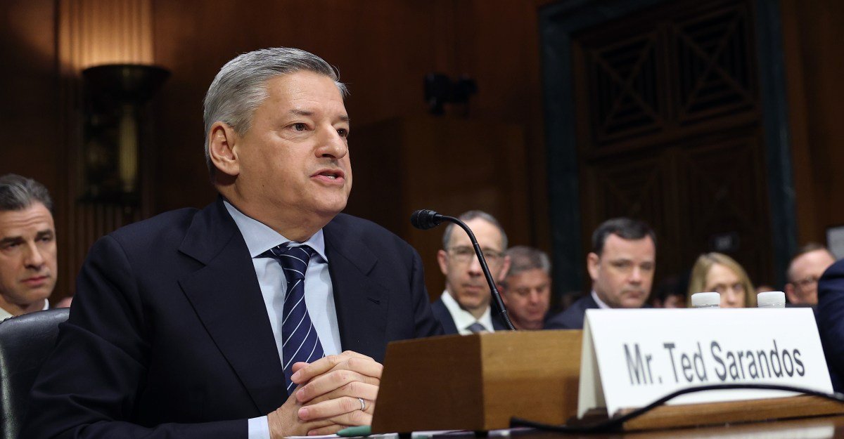 Netflix Co-CEO Ted Sarandos testifies before a Senate Judiciary Committee, flanked by Warner Bros. Discovery Chief Revenue and Strategy Officer Bruce Campbell, amidst a contentious hearing.