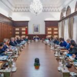 Photo du Chef du gouvernement Aziz Akhannouch présidant un Conseil de gouvernement, avec des documents et des officiels en arrière-plan.