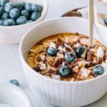 A steaming bowl of oatmeal topped with fresh berries, nuts, and a drizzle of honey, symbolizing a healthy breakfast.