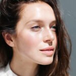 A person applying a gentle milky cleanser to their face, symbolizing a balanced skincare routine for oily dehydrated skin.