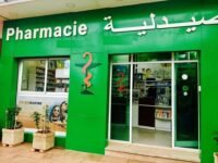 Un pharmacien marocain en blouse blanche, l'air déterminé, devant une rangée de médicaments, symbolisant la résistance de la profession face aux réformes proposées par le Conseil de la concurrence et la menace de grève.