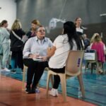 Des personnes discutant lors d'un forum pour l'emploi, avec des stands d'entreprises et des demandeurs d'emploi. L'ambiance est active et professionnelle, symbolisant la recherche d'opportunités.