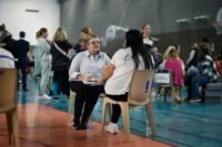 Des personnes discutant lors d'un forum pour l'emploi, avec des stands d'entreprises et des demandeurs d'emploi. L'ambiance est active et professionnelle, symbolisant la recherche d'opportunités.