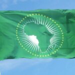 Logo de l'Union Africaine avec des drapeaux des pays membres en arrière-plan, symbolisant les enjeux diplomatiques en Afrique du Nord.