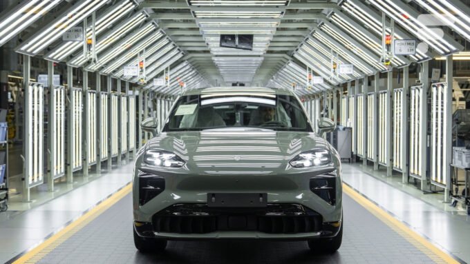 Vue d'ensemble de la ligne de production du Porsche Cayenne électrique à l'usine Volkswagen de Bratislava, montrant des véhicules en cours d'assemblage et des robots industriels.
