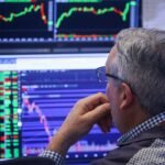 A trader works on the floor of the New York Stock Exchange, symbolizing financial market activity and potential volatility.