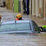 Une image symbolisant les aléas climatiques en Europe, comme une ville partiellement inondée, ou un paysage aride sous un soleil de plomb, avec des silhouettes de personnes en arrière-plan.
