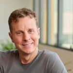 Jamie Siminoff, founder of Ring, standing with a Ring video doorbell