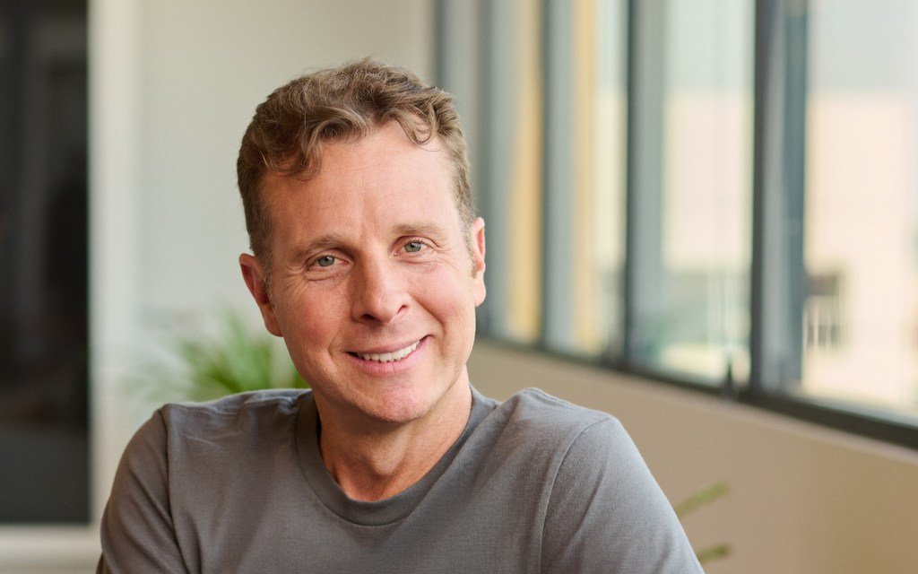 Jamie Siminoff, founder of Ring, standing with a Ring video doorbell