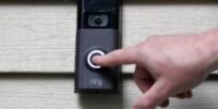 Amazon Ring doorbell camera with Flock Safety logo in the background, symbolizing the terminated partnership and public privacy concerns.