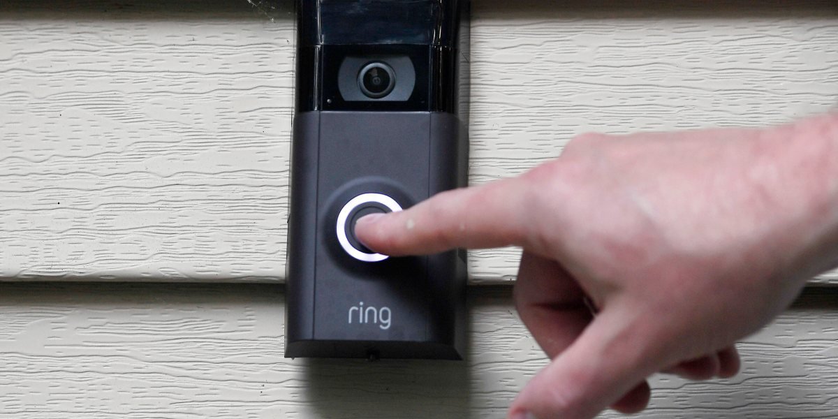 Amazon Ring doorbell camera with Flock Safety logo in the background, symbolizing the terminated partnership and public privacy concerns.
