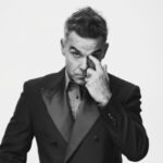 Robbie Williams en concert, micro à la main, devant une foule enthousiaste