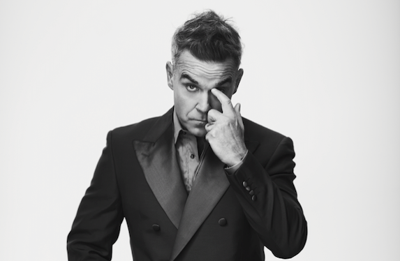 Robbie Williams en concert, micro à la main, devant une foule enthousiaste
