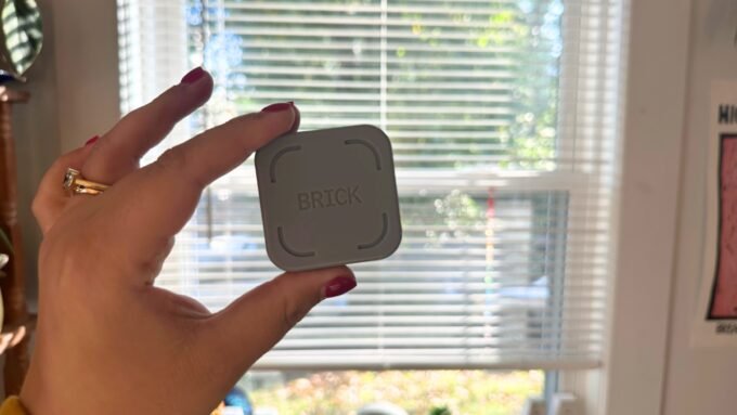 A smartphone being tapped against 'The Brick' device, illustrating screen time management.