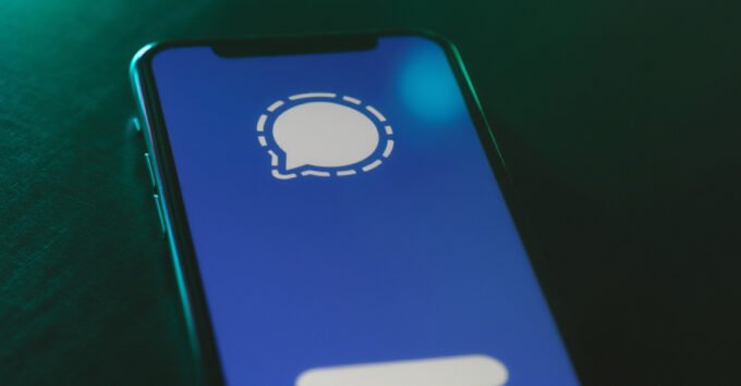 Illustration of a smartphone with the Signal app logo, overlaid with a phishing hook or a warning symbol, representing cyber threats to secure messaging.