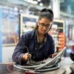 The AI Revolution: Why Young Professionals Are Pivoting to Skilled Trades 4 Young worker in a hard hat looking at a digital tablet, symbolizing the blend of traditional trades and modern technology.