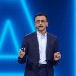 Snowflake CEO Frank Slootman speaking at a tech conference, with a graphic representing data flowing into AI models in the background.