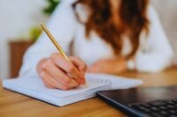 A hand writing on a single sheet of paper, symbolizing a founder's strategic one-page plan to prevent burnout.