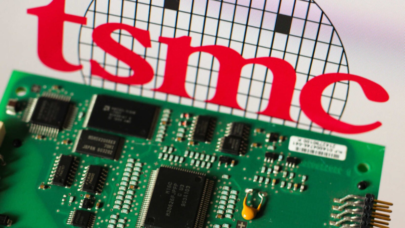 Taiwan Semiconductor Manufacturing Company (TSMC) logo next to a printed circuit board, symbolizing the island's critical role in global chip production.