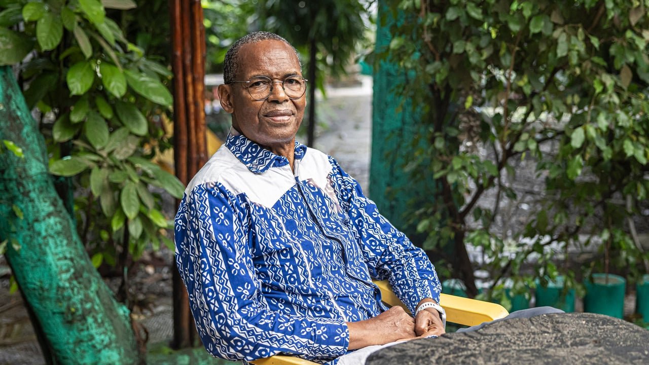 Portrait de l'écrivain guinéen Tierno Monénembo à Conakry, regardant au loin avec une expression pensive.