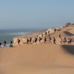 Groupe de femmes en pleine randonnée dans un paysage marocain ensoleillé, symbolisant l'aventure et la solidarité du Trek des Gazelles.