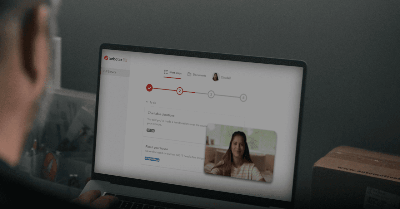 A person using the TurboTax mobile app on a smartphone to file their taxes, with a calculator and documents nearby.