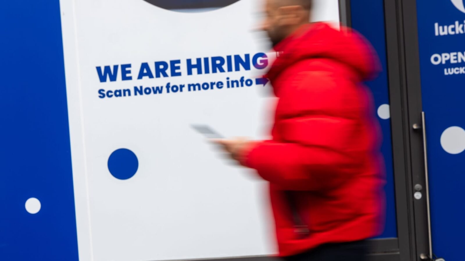 A 'now hiring' sign displayed in a Manhattan business window, symbolizing the state of the job market.