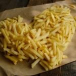 A couple enjoying a budget-friendly meal with heart-shaped pizza and drinks on Valentine's Day.