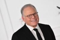 Warner Bros. Discovery logo with streaming icons and stock tickers representing Netflix and Paramount