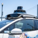 A Waymo autonomous vehicle navigating a city street, representing urban mobility and self-driving technology.