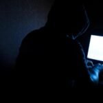 A magnifying glass over crypto logos, symbolizing ZachXBT's investigation into insider trading.