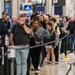 TSA Paychecks Return, But Air Travel Turbulence Persists 4 TSA agents working at an airport security checkpoint with travelers in the background.