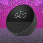 Amazon Echo Spot smart alarm clock displaying time and weather on a bedside table.